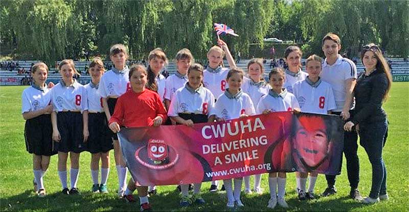 Group of school children holding a CWUHA banner